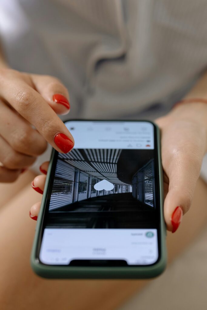 pexels-photo-6963585-6963585 A woman with red nails uses a smartphone to browse social media indoors.